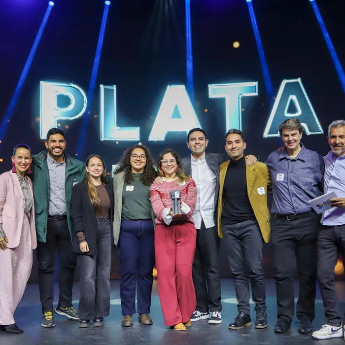 Equipos de Modista y Cebra celebrando en el escenario junto al letrero “Plata” de los IAB MIXX Chile 2026, con el trofeo en las manos.